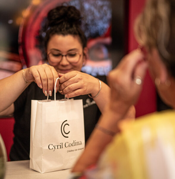 une jeune fille emballant des produits dans un sac acheté par une cliente de la vinaigrerie cyril codina